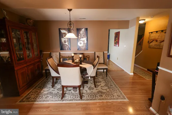 a dining room with wooden floor a chandelier a wooden table and chairs