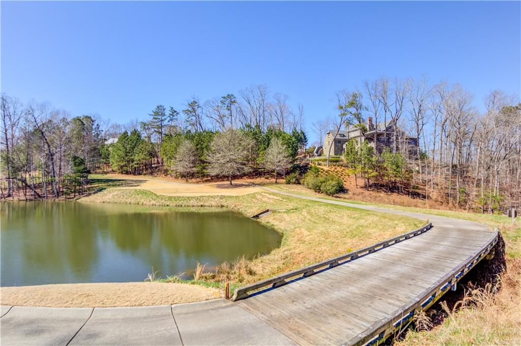 4921 Roaring Fork Pass Suwanee, GA 30024 - Photo 6 of 9 a view of a swimming pool with a lake and trees in the back