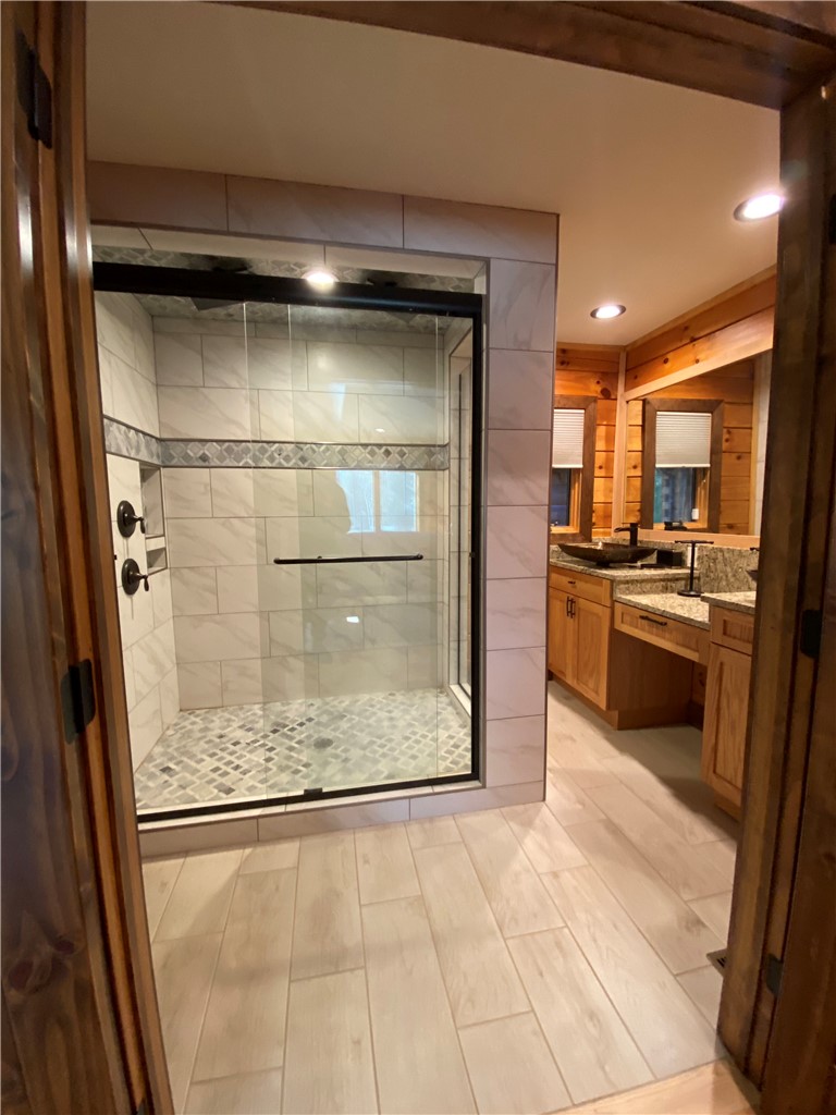 128 McAlister Road West Union, SC 29696 - Photo 21 of 40 Luxurious tile-surrounded shower with a glass enclosure, accompanied by a double vanity featuring modern fixtures.