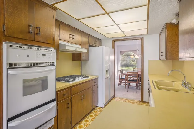 a kitchen with stainless steel appliances granite countertop a stove a refrigerator and a dining table with granite countertops