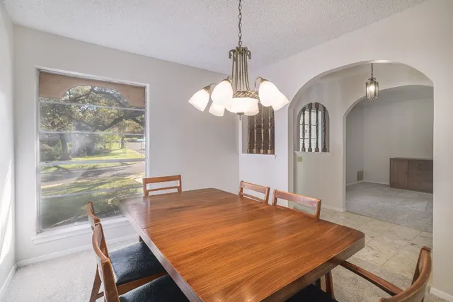 a dining room with wooden floor a chandelier a wooden table and chairs