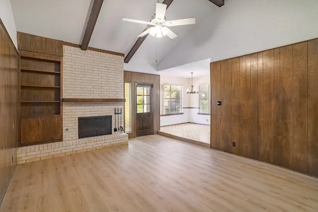 a view of an empty room with a fireplace and a ceiling fan