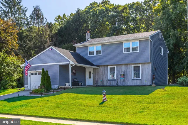 a view of a brick house with a yard and large trees