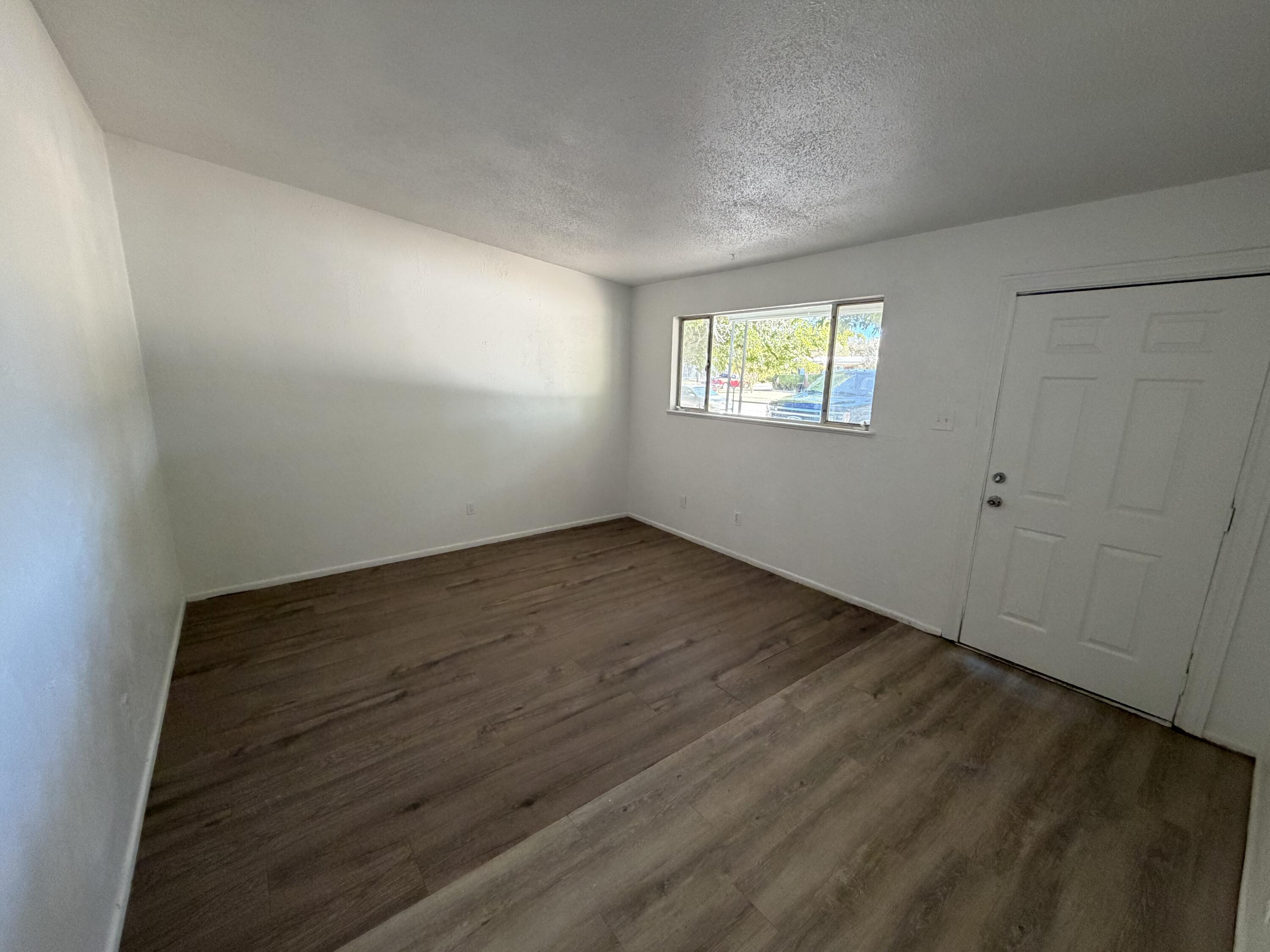 6004 Peoria Avenue Lubbock, TX 79413 - Photo 2 of 7 an empty room with wooden floor and windows