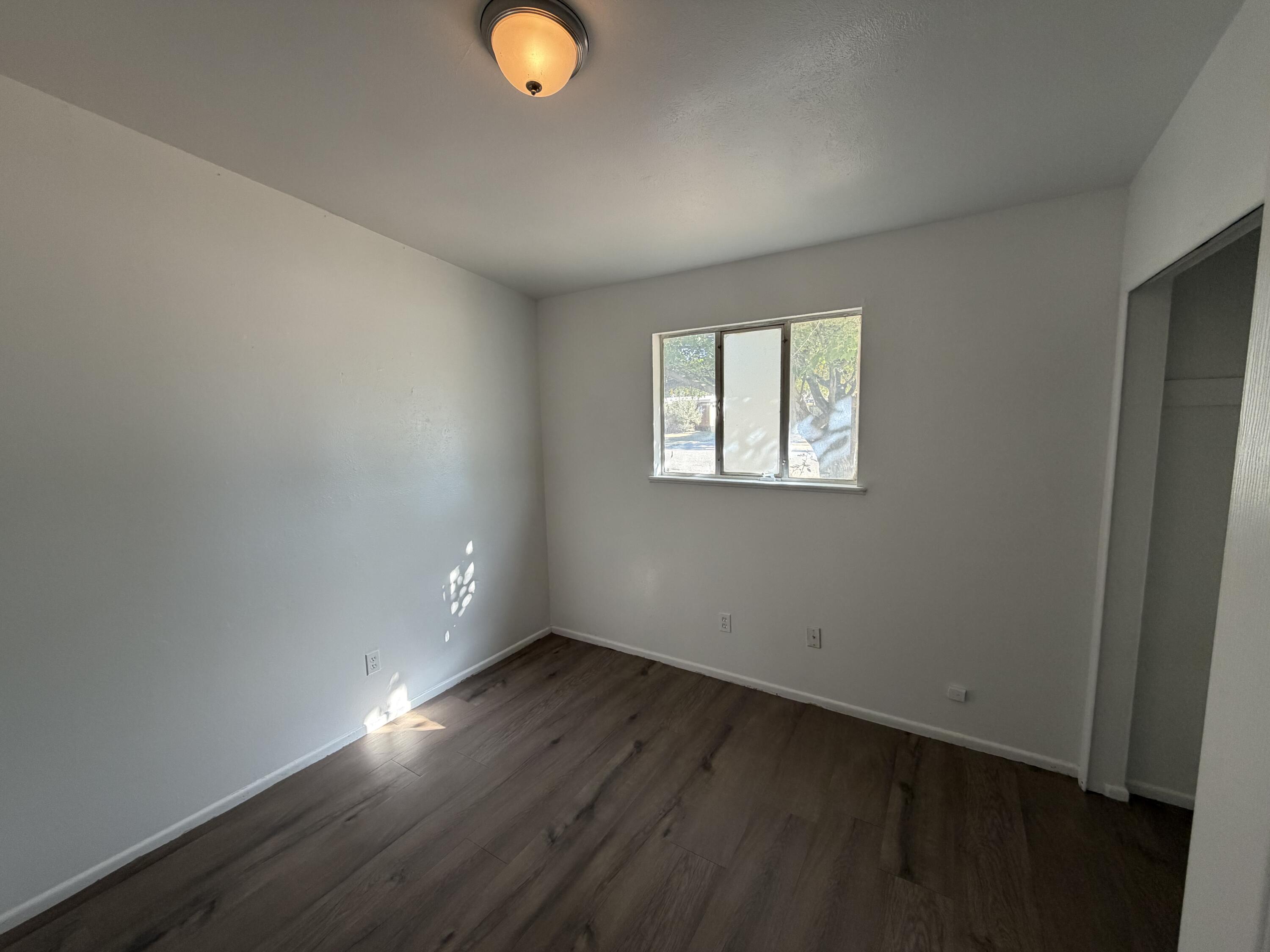 6004 Peoria Avenue Lubbock, TX 79413 - Photo 3 of 7 an empty room with wooden floor and windows