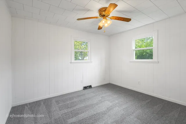 an empty room with a window and a fan