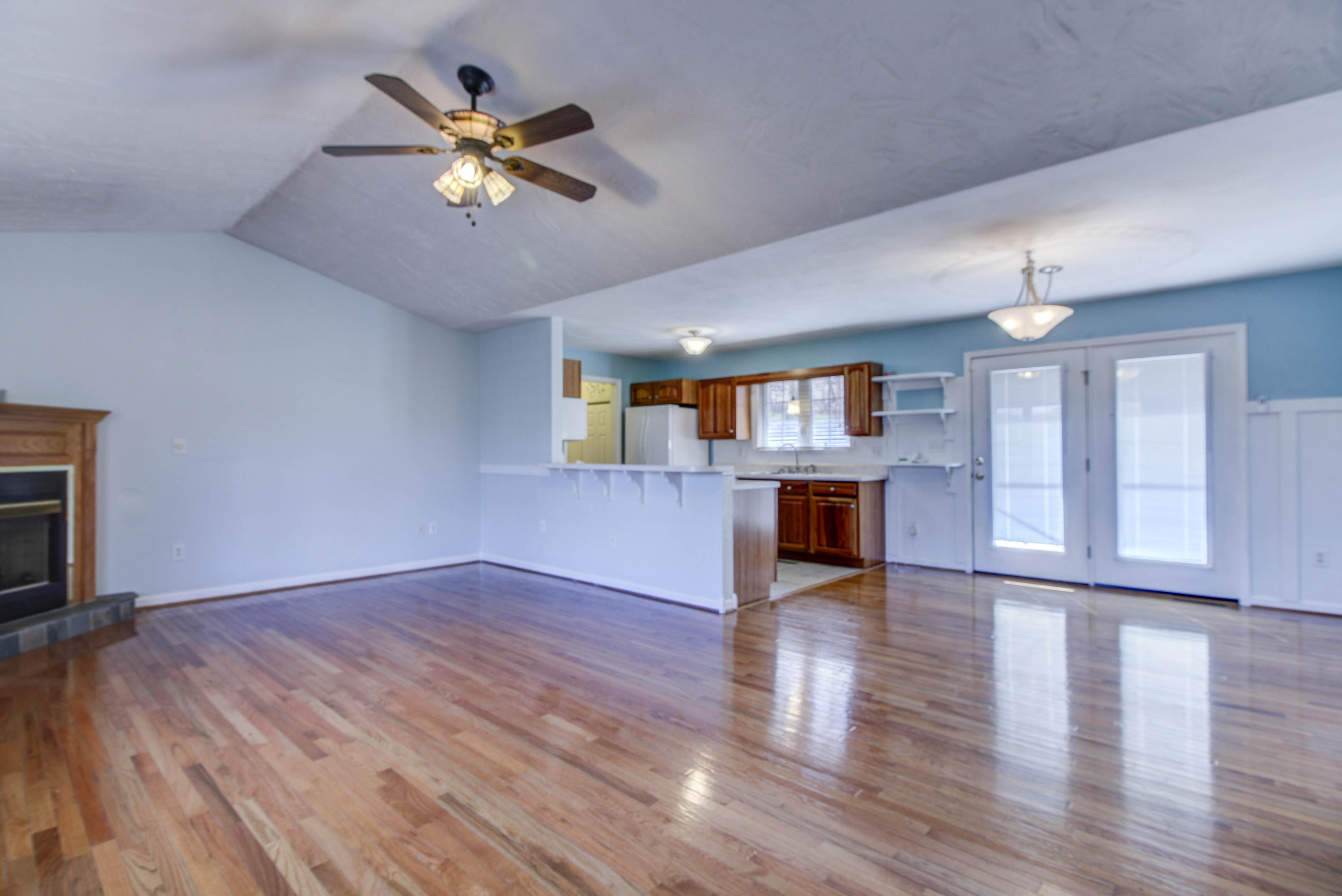 1546 Pike Road Montvale, VA 24122 - Photo 11 of 44 an empty room with wooden floor a ceiling fan a fireplace and windows