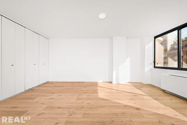 a view of empty room with wooden floor and windows