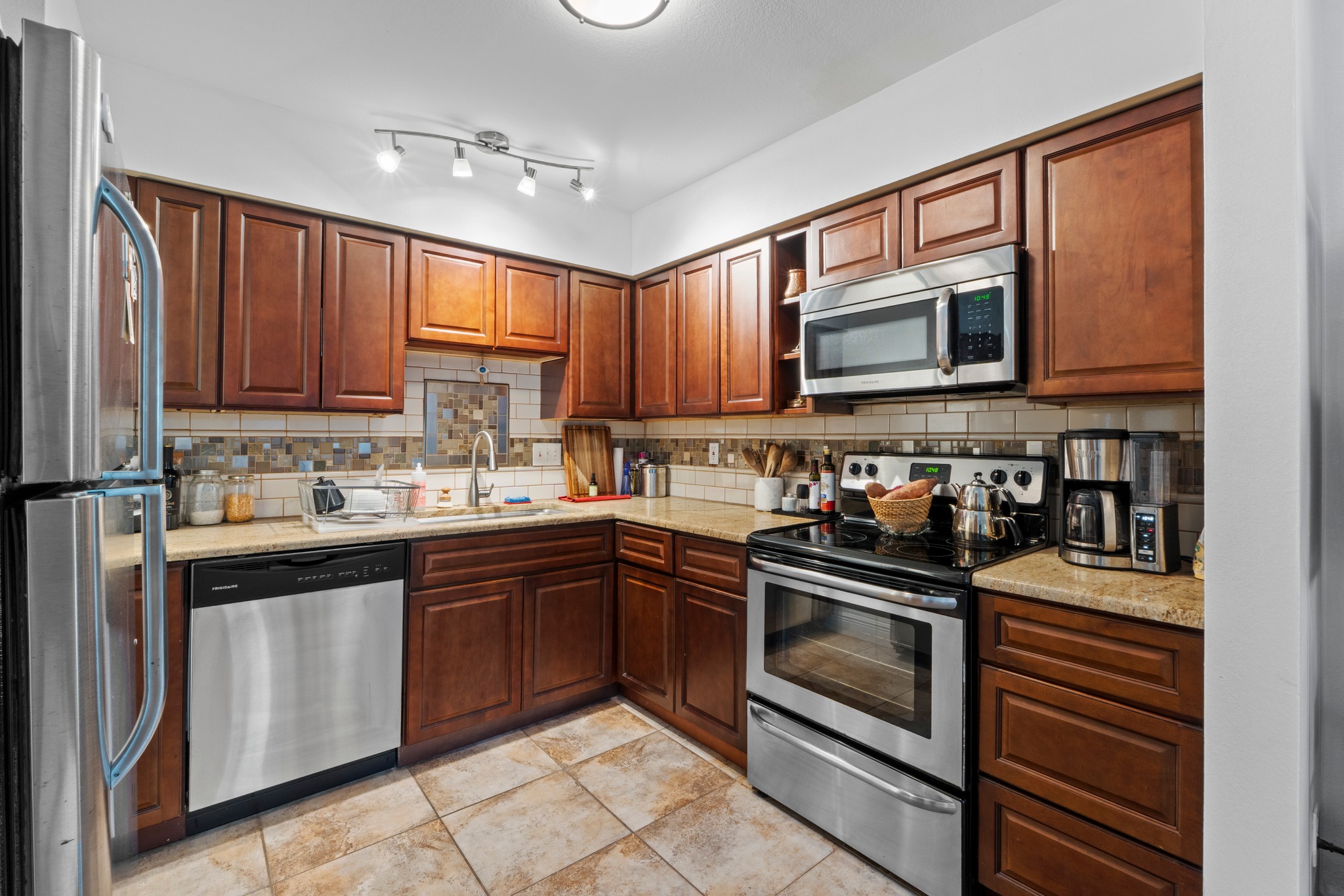1750 Timber Ridge Road, Unit 102 Austin, TX 78741 - Photo 3 of 24 a kitchen with granite countertop wooden cabinets a stove top oven and stainless steel appliances