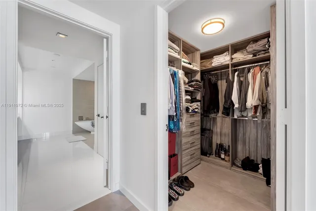 a view of walk in closet with clothes and shoes