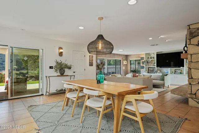 a kitchen with stainless steel appliances kitchen island granite countertop a dining table chairs and white cabinets