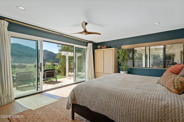 a bed sitting in a spacious bedroom next to a large window