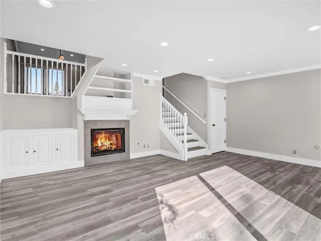 a view of an empty room with wooden floor and a fireplace