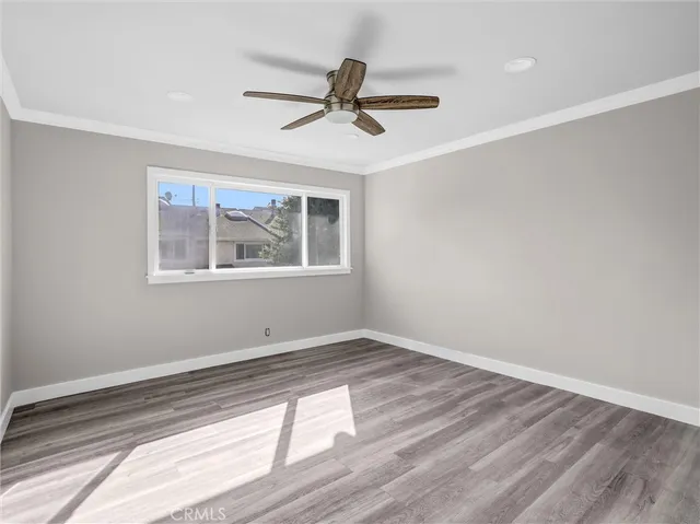 a view of empty room with wooden floor and fan