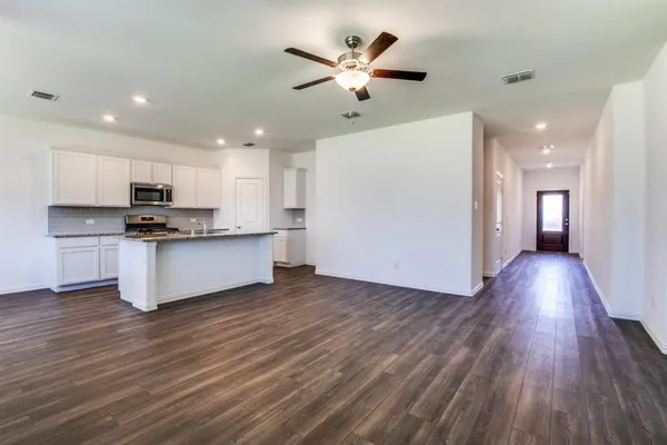 a view of kitchen with granite countertop wooden floors white cabinets and stainless steel appliances