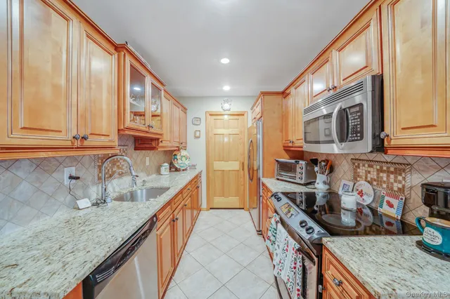 a kitchen with stainless steel appliances granite countertop a stove a sink and a microwave