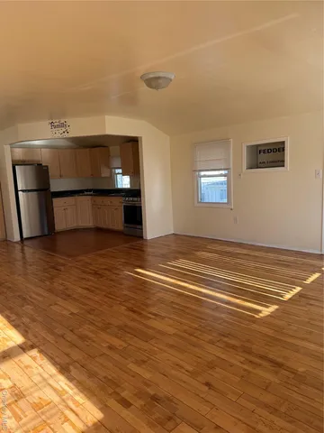 a view of kitchen and empty room with wooden floor