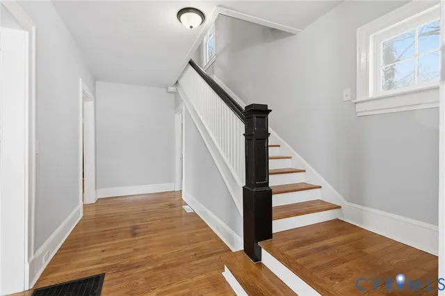 a view of a hallway with wooden floor and staircase