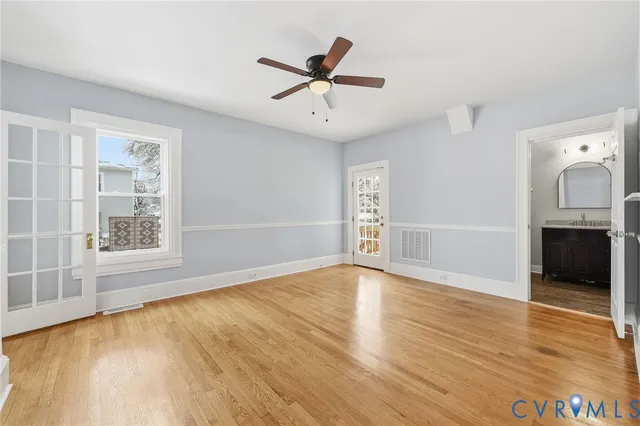 an empty room with wooden floor fan and windows