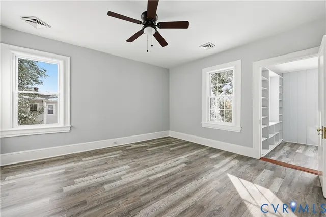 a view of an empty room with window and wooden floor