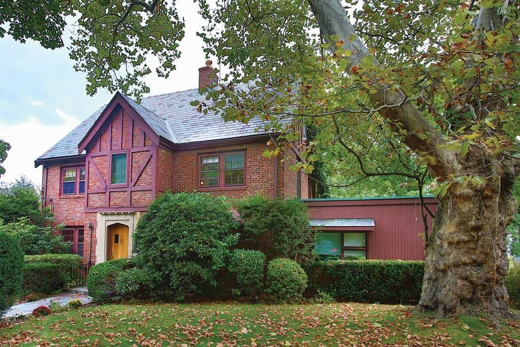a brick house with large windows and plants