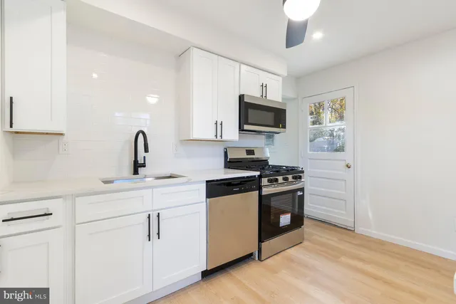 a kitchen with cabinets stainless steel appliances and wooden floor