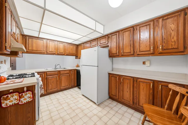 a kitchen with stainless steel appliances granite countertop a refrigerator a stove a sink dishwasher and wooden cabinets