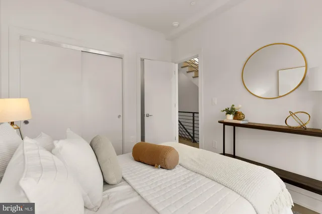 a bedroom with a bed a mirror and a potted plant