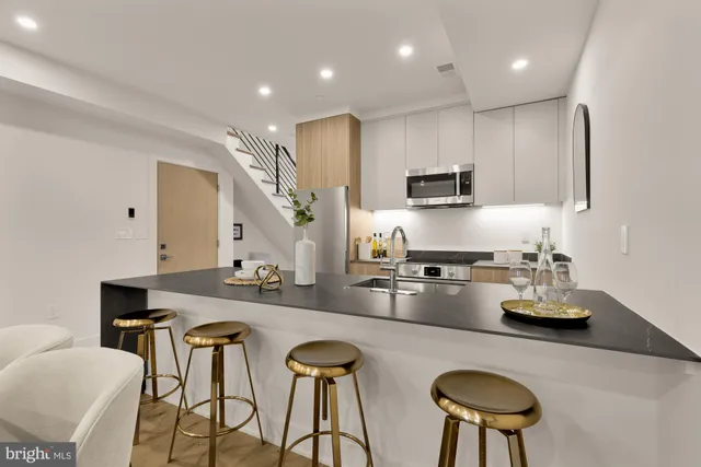 a kitchen with stainless steel appliances granite countertop a stove top oven a sink a dining table and chairs with wooden floor