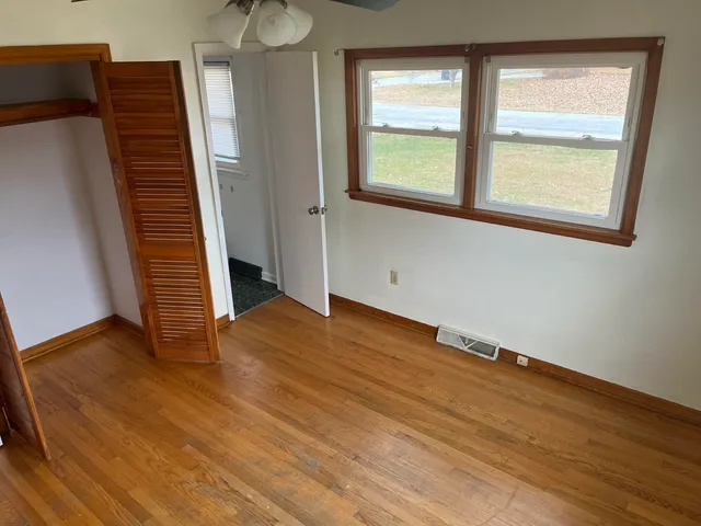 a view of an empty room with wooden floor and a window