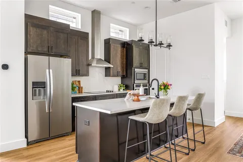 a kitchen with stainless steel appliances a refrigerator a sink a stove a dining table and chairs