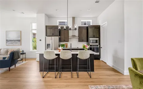 a dining room with stainless steel appliances kitchen island granite countertop a table chairs and a refrigerator