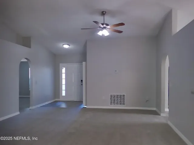 a view of an empty room with a chandelier fan