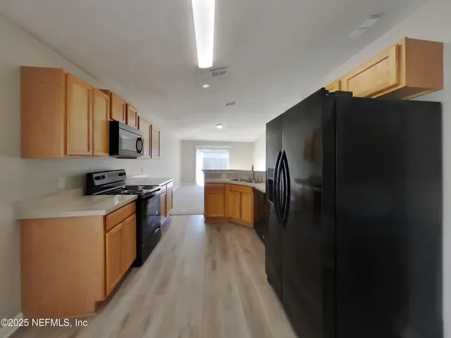 a kitchen with stainless steel appliances granite countertop a refrigerator a stove top oven a sink and dishwasher