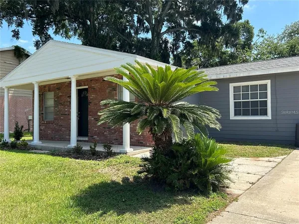 a view of a house with a yard potted plants and large tree