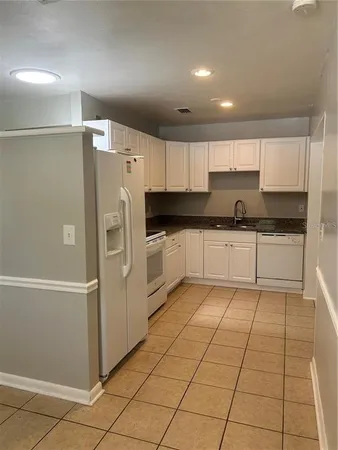 a kitchen with granite countertop a refrigerator and a sink