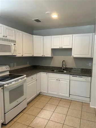 a kitchen with granite countertop white cabinets stainless steel appliances and sink