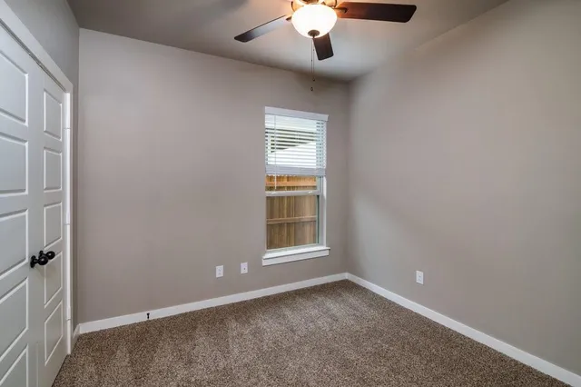 an empty room with a window and chandelier fan