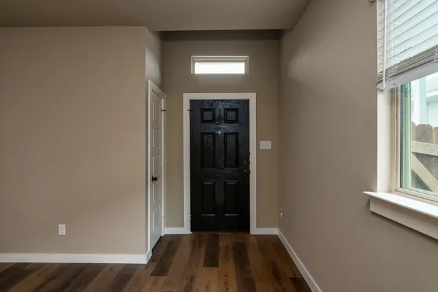 an empty room with wooden floor cabinet and windows