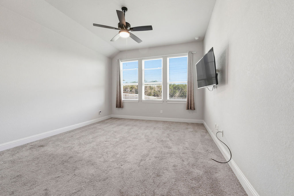 2032 Base Burner Path Leander, TX 78641 - Photo 29 of 34 Spacious room featuring light gray carpeting, a large three-panel window with blinds and drapes, and a ceiling fan with integrated lighting