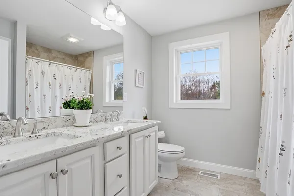 a bathroom with a granite countertop sink a toilet and a mirror
