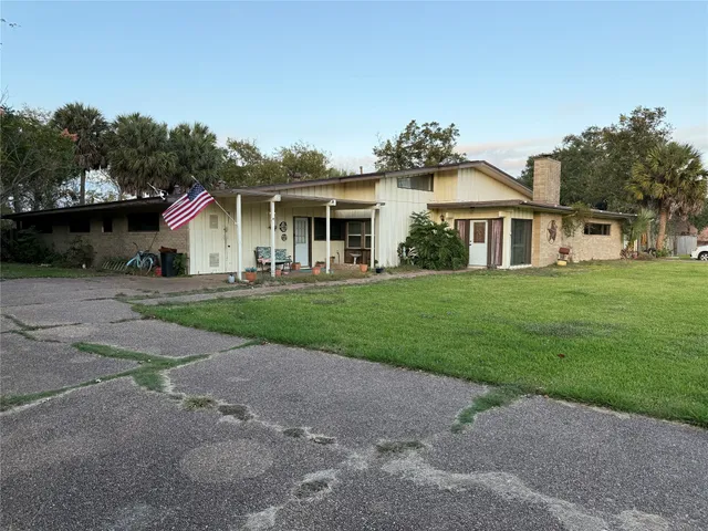 a front view of a house with a garden and trees