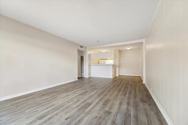 a view of empty room with wooden floor and window