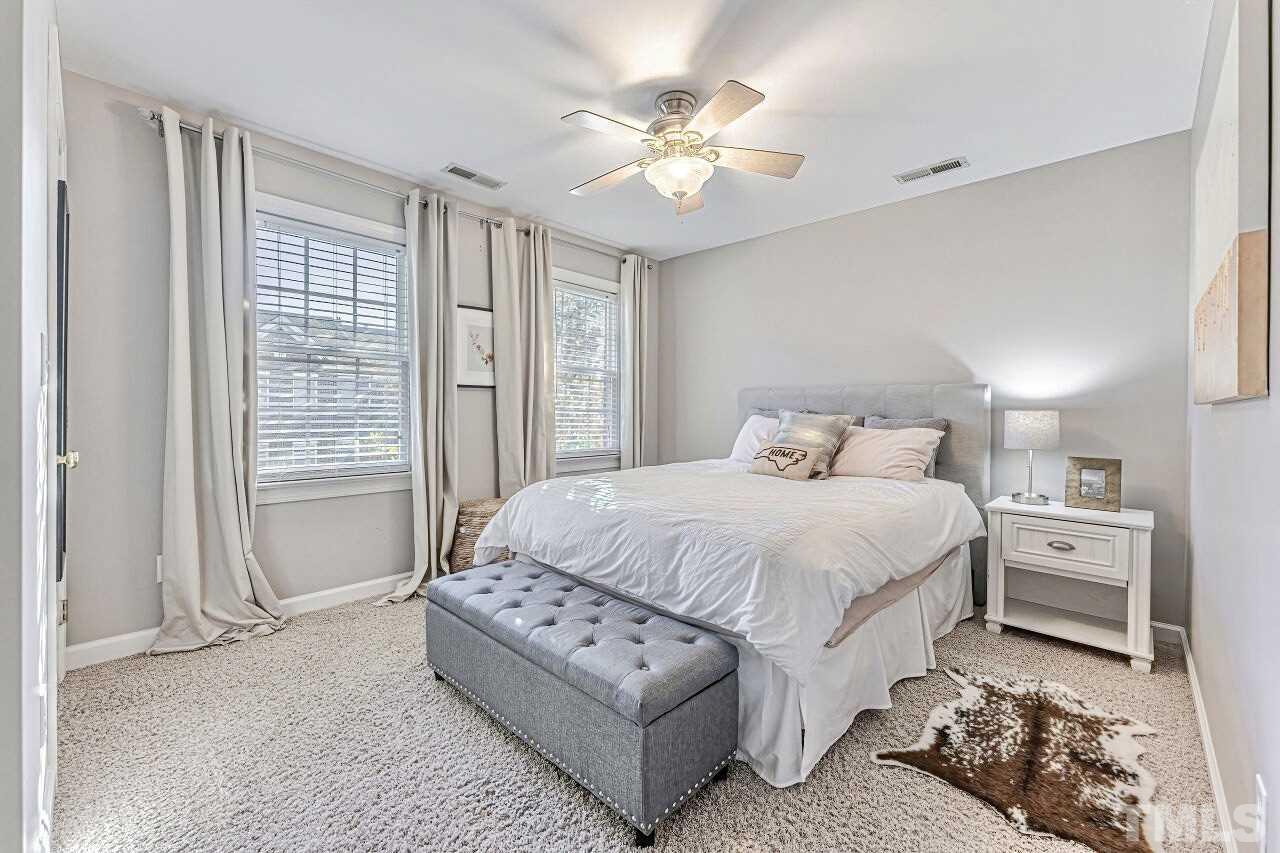 125 Fenner Lane Raleigh, NC 27603 - Photo 17 of 30 a spacious bedroom with a bed and a chandelier