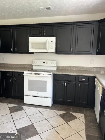 a kitchen with granite countertop a stove top oven microwave and cabinets
