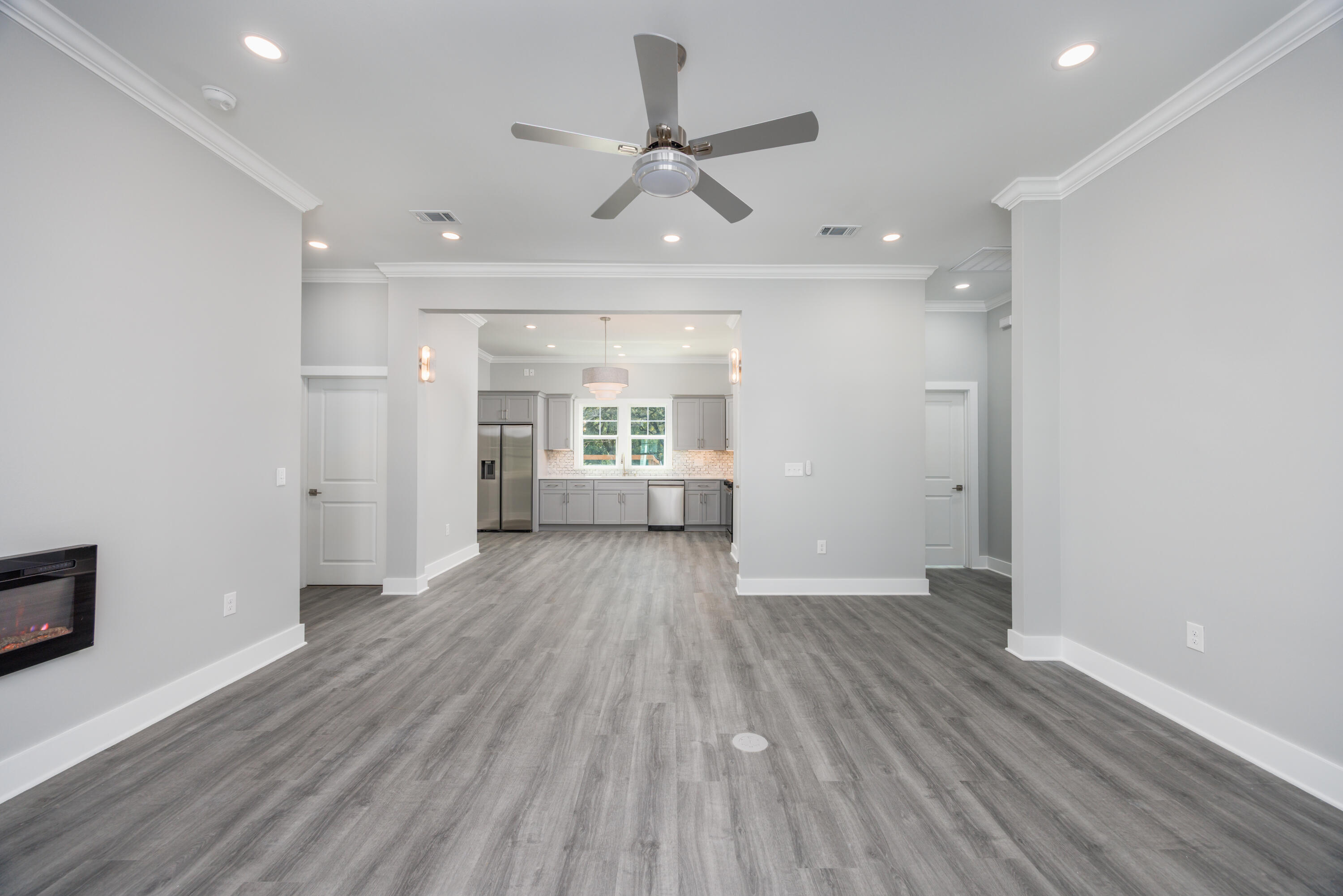 26 Shebbi Lane Freeport, FL 32439 - Photo 4 of 19 an empty room with wooden floor a ceiling fan and kitchen view