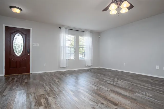 an empty room with wooden floor mirror and windows