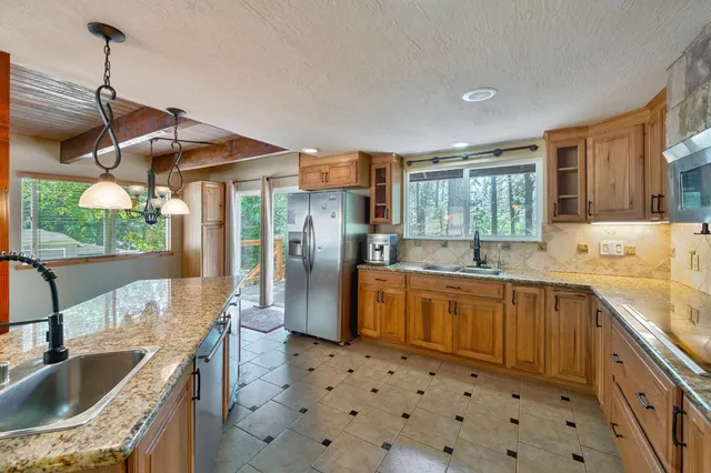 a kitchen with granite countertop a sink a counter top space and stainless steel appliances