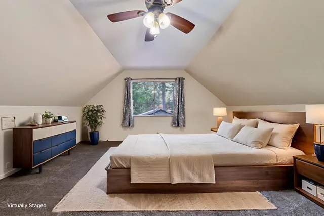 a bedroom with a large bed and a chandelier fan