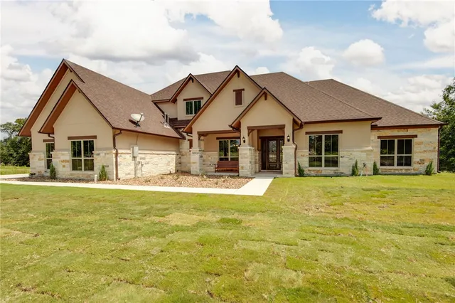 a front view of a house with a garden and yard